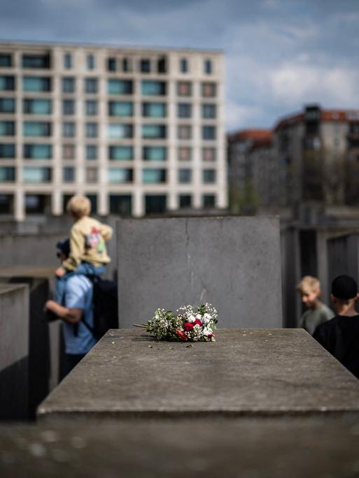 Ein Blumenstrauß liegt im April 2025 auf einer Betonstele des  Denkmals für die ermordeten Juden Europas in Berlin