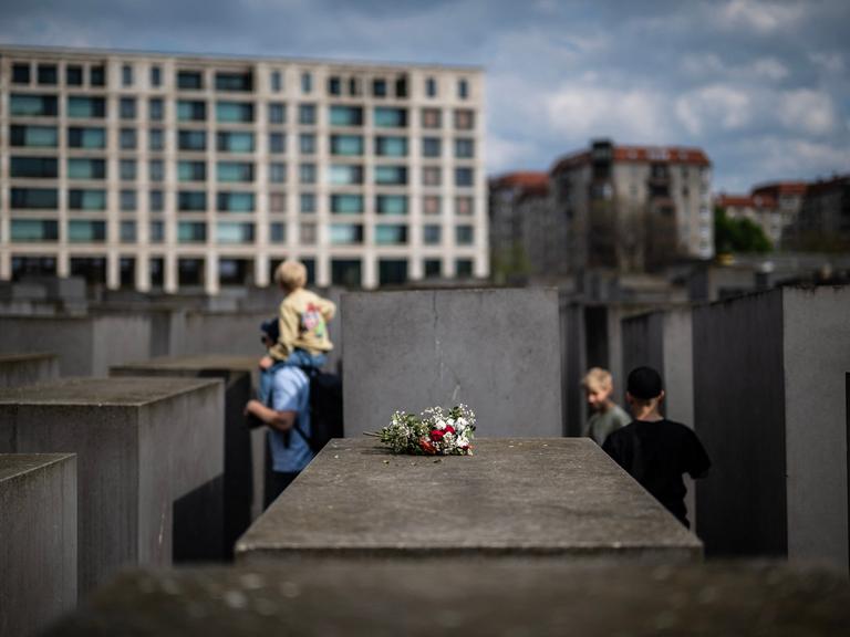 Ein Blumenstrauß liegt im April 2025 auf einer Betonstele des  Denkmals für die ermordeten Juden Europas in Berlin