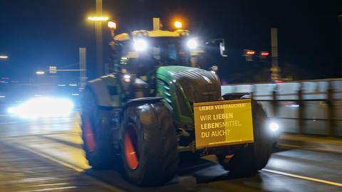 Sachsen, Leipzig: Einer von mehreren Landwirten fährt mit seinem Traktor und einem Protestplakat am frühen Morgen durch den beginnenden Berufsverkehr.