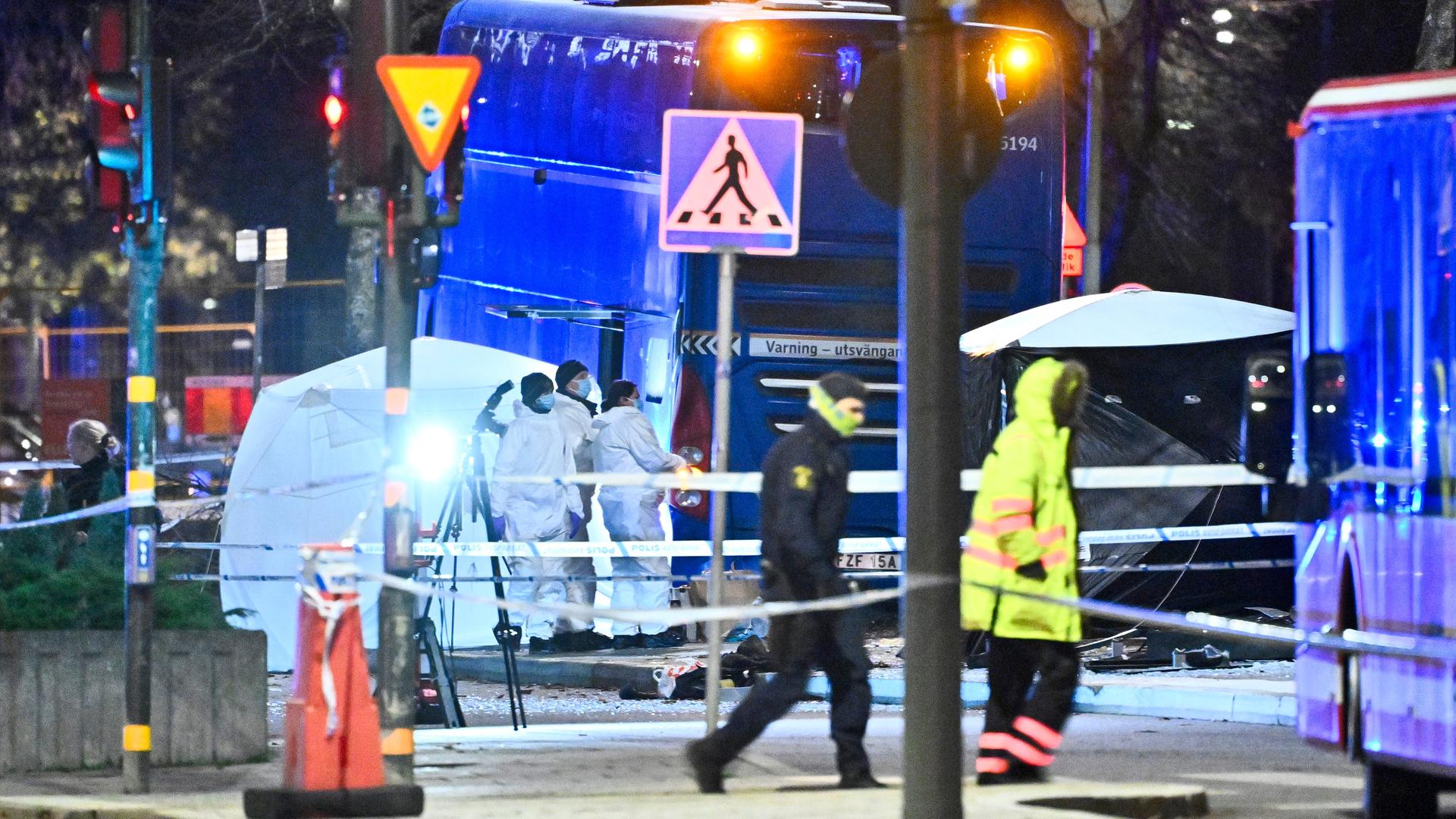 Polizisten untersuchen bei Flutlicht die Unfallstelle eines Busunfalls in Stockholm. Polizisten untersuchen bei Flutlicht die Unfallstelle eines Busunfalls in Stockholm.