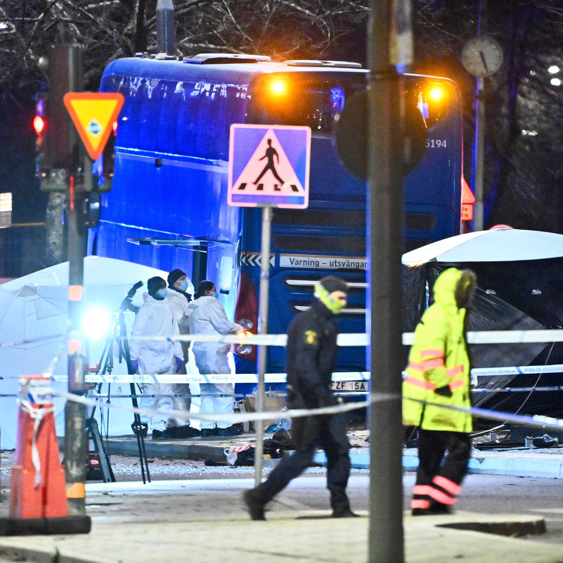 Polizisten untersuchen bei Flutlicht die Unfallstelle eines Busunfalls in Stockholm. 
