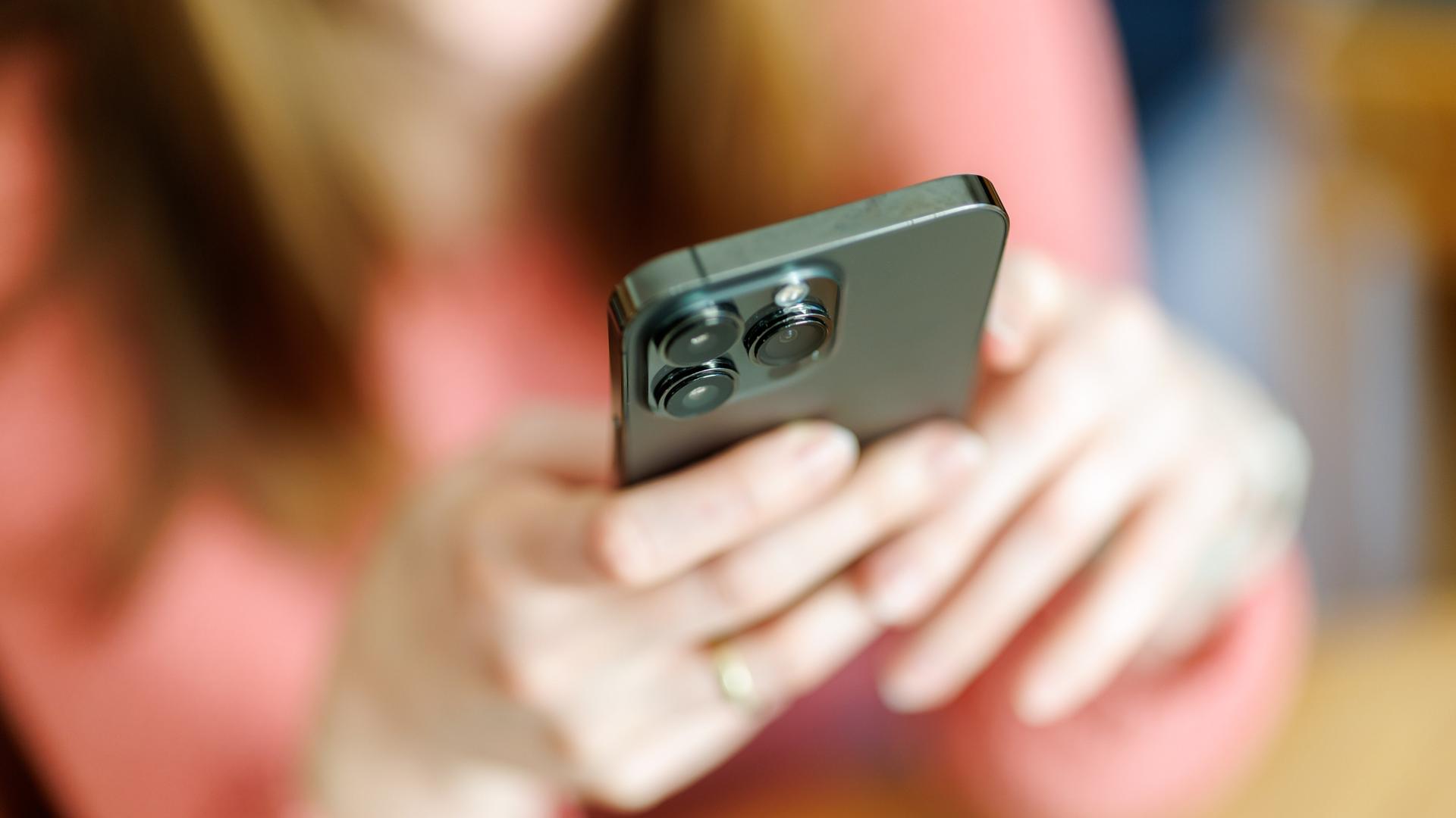 Eine junge Frau benutzt ein Smartphone. Das Bild der Frau ist verschwommen.