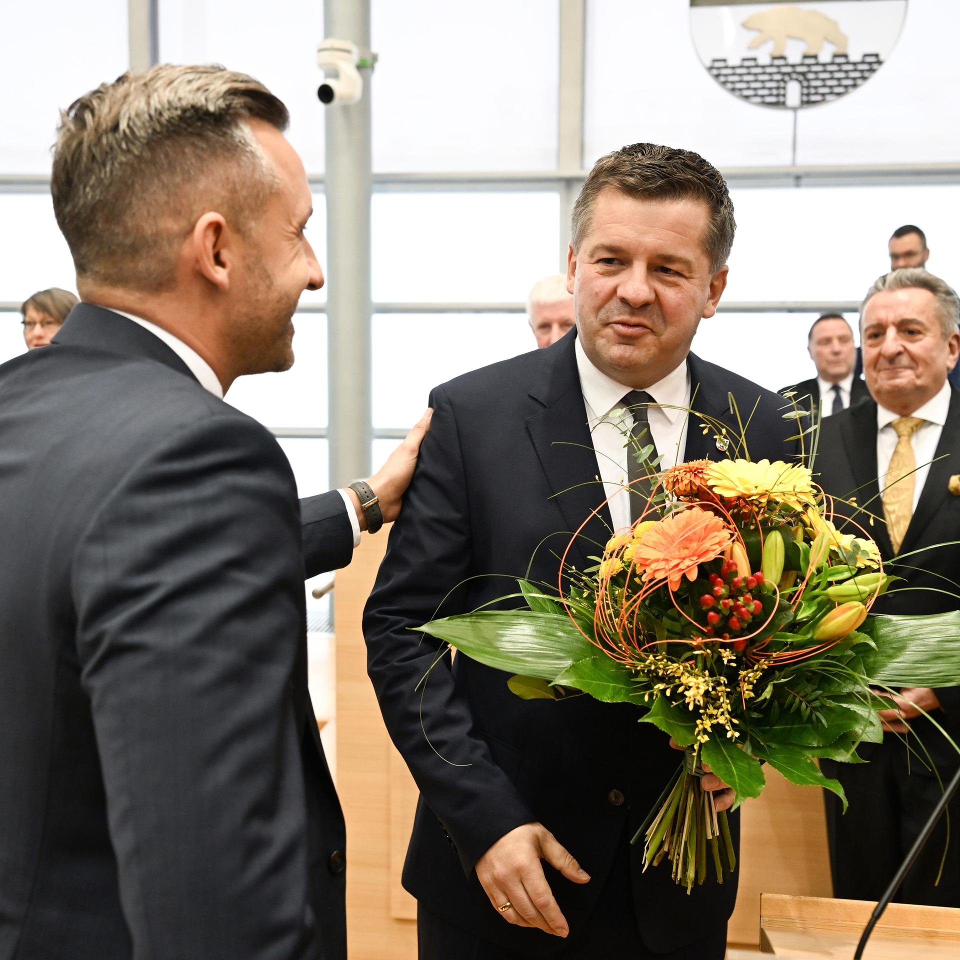 Sven Schulze (CDU) nimmt Blumen im Plenarsaal des Landtages von Sachsen-Anhalt entgegen. Ulrich Siegmund (AFD,l) gratuliert, nachdem Schulze zum neuen Ministerpräsidenten des Landes gewählt wurde. 