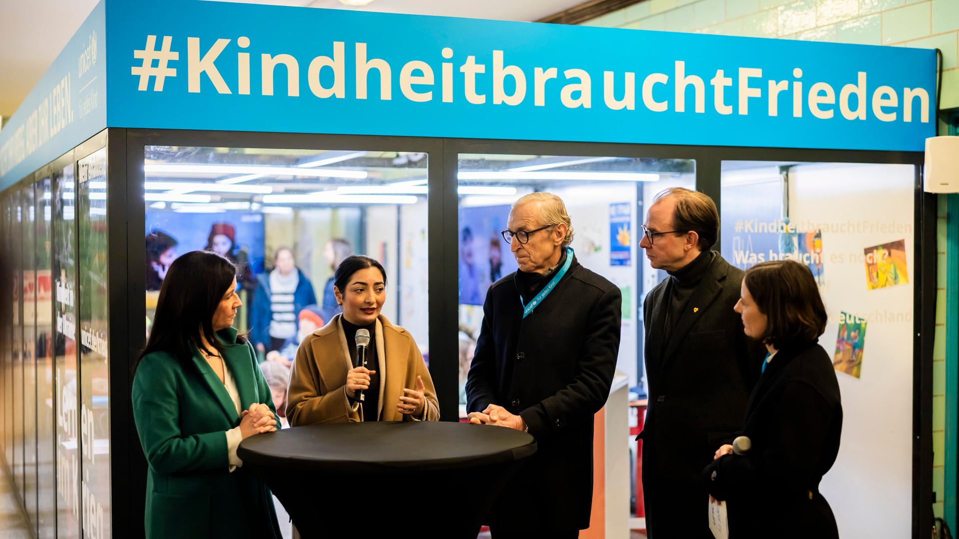 Mehrere Personen stehben bei der Eröffnung der Unicef-Aktion "Kindheit in der Ukraine: Lernen im Krieg" im U-Bahnhof Alexanderplatz. 