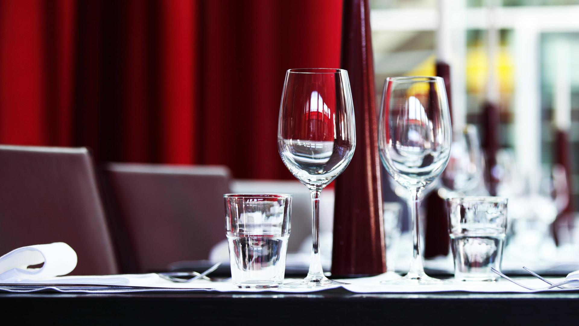 Ein eingedeckter Tisch mit Weingläsern, Wassergläsern und Geschirr in einem Restaurant
