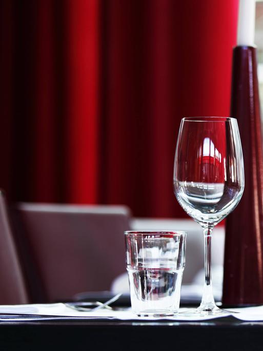 Ein eingedeckter Tisch mit Weingläsern, Wassergläsern und Geschirr in einem Restaurant 