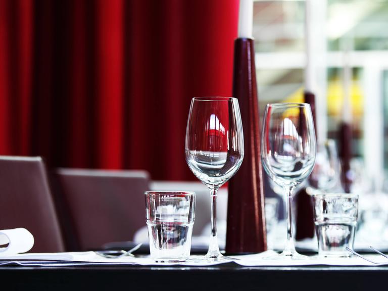 Ein eingedeckter Tisch mit Weingläsern, Wassergläsern und Geschirr in einem Restaurant 
