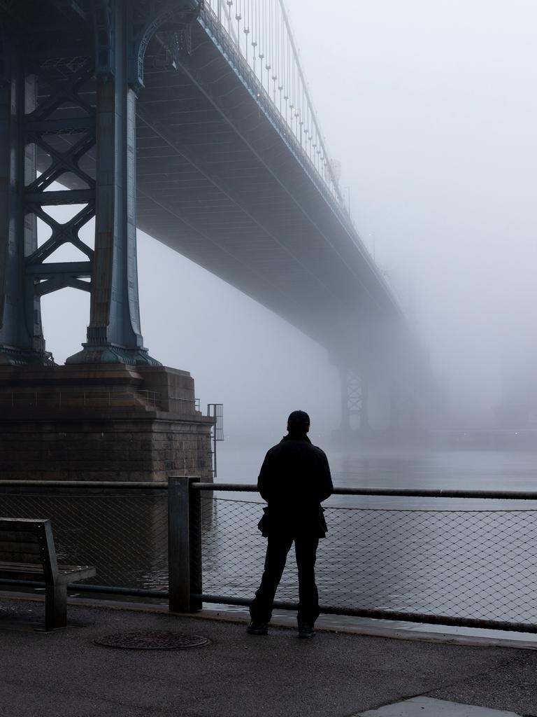 Eine Person steht im dichten Nebel unter der Manhattan Bridge. (Symbolbild)