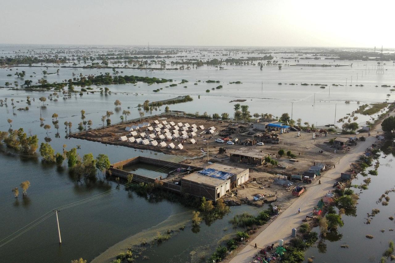 Luftaufnahme einer ländlichen Region, die fast vollständig überflutet ist. Im Zentrum des Bildes wurden auf einer Landzunge einige Zelte errichtet.
