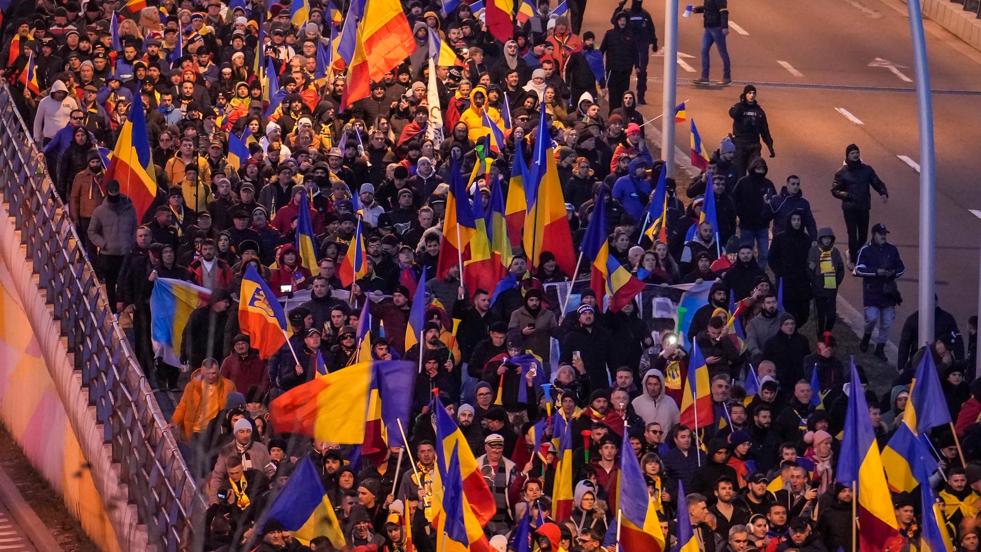 Demonstranten gehen durch das Zentrum von Bukarest. Sie schwingen rumänische Fahnen. 