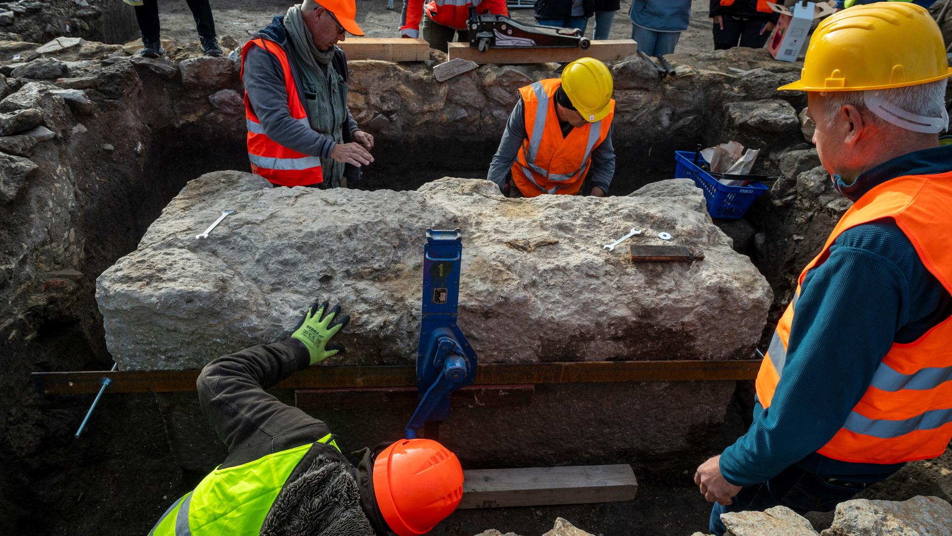 Arbeiter sichern den Deckel des steinernen Sarges.