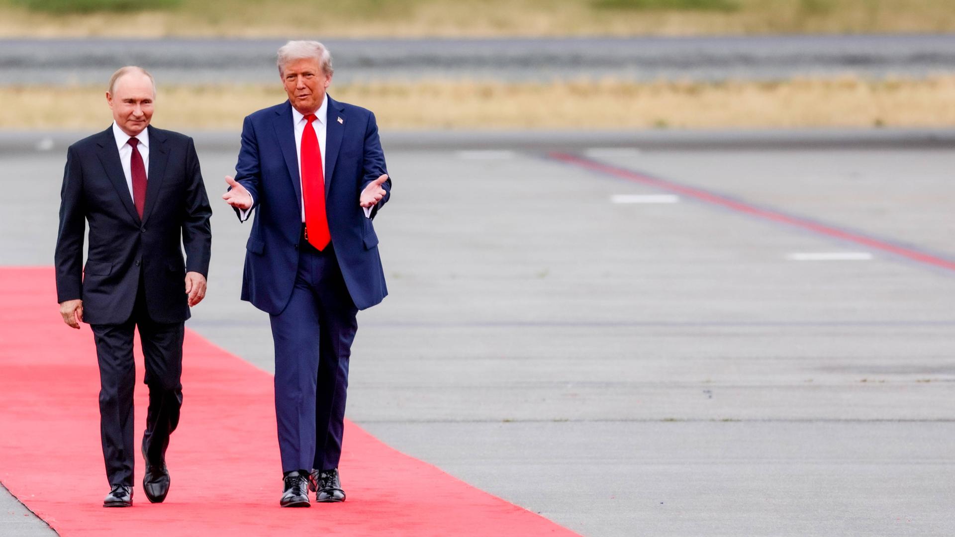 Zwei Männer in Anzug laufen über einen roten Teppich. Es sind der russische Präsident Wladimir Putin und sein US-Amtskollege Donald Trump.