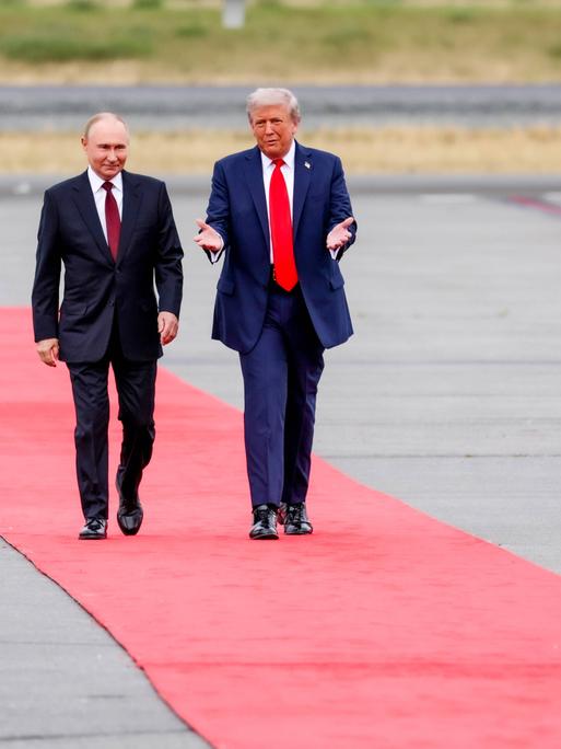 Zwei Männer in Anzug laufen über einen roten Teppich. Es sind der russische Präsident Wladimir Putin und sein US-Amtskollege Donald Trump.
