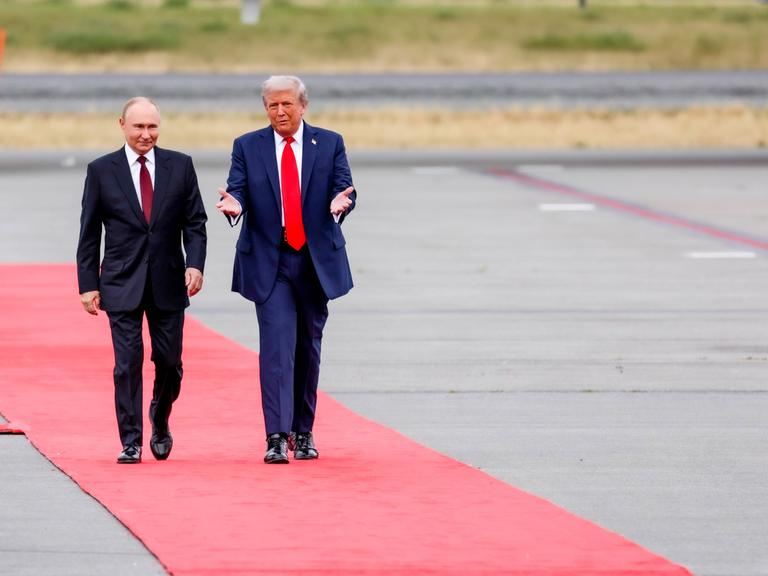 Zwei Männer in Anzug laufen über einen roten Teppich. Es sind der russische Präsident Wladimir Putin und sein US-Amtskollege Donald Trump.