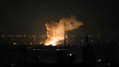 Nach einer Explosion, die den dunklen Nachthimmel über einer Stadt erhellt, steigt Rauch auf.