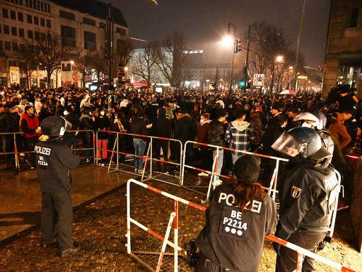 Polizisten stehen hinter einer Absperrung am Brandenburger Tor in Berlin, wo sich mehrere hundert Menschen versammelt haben (aufgenommen in der Silvesternacht zum Jahreswechsel 2022/2023) 