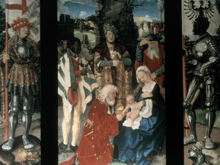 Hans Baldung-Griens Tryptichon "Anbetung der Heiligen drei Könige" zeigt mittig die heiligen drei Könige, davor kniet ein bärtiger Mann vor Maria, die das Jesuskind auf dem Schoß hält.