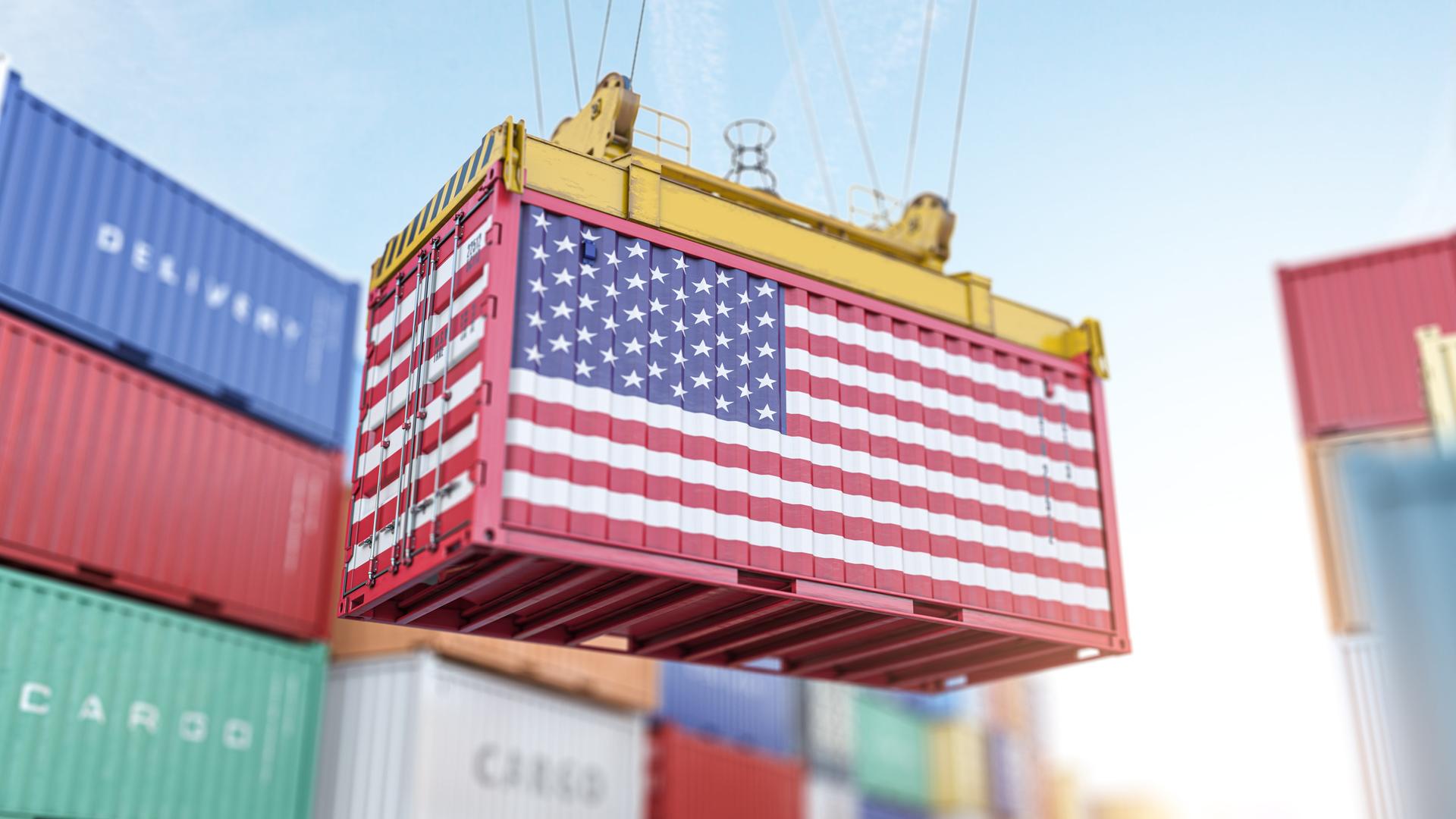 Symbolbild: Ein Frachtcontainer mit USA-Flagge in einem Hafen beim verladen.