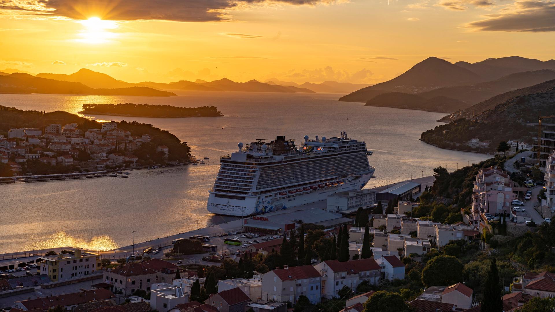 n Ein Kreuzfahrtschiff verlässt bei Sonnenuntergang die kroatische Stadt Dubrovnik.