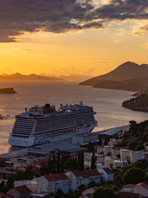 n Ein Kreuzfahrtschiff verlässt bei Sonnenuntergang die kroatische Stadt Dubrovnik.