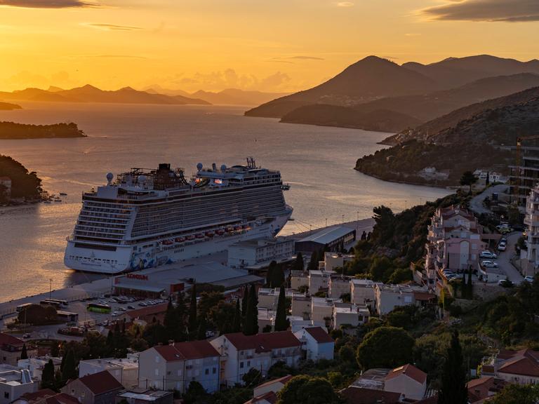 n Ein Kreuzfahrtschiff verlässt bei Sonnenuntergang die kroatische Stadt Dubrovnik.