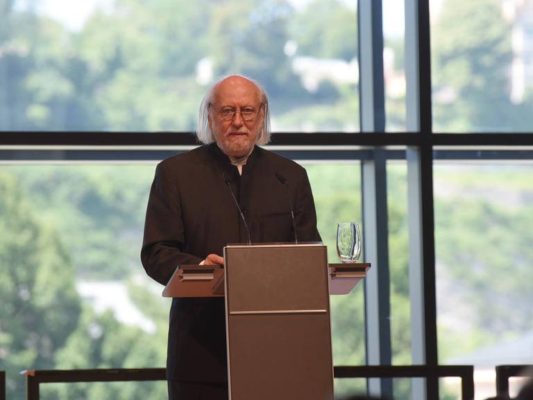 Der ungarische Schriftsteller Laszlo Krasznahorkai steht an einem Rednerpult.