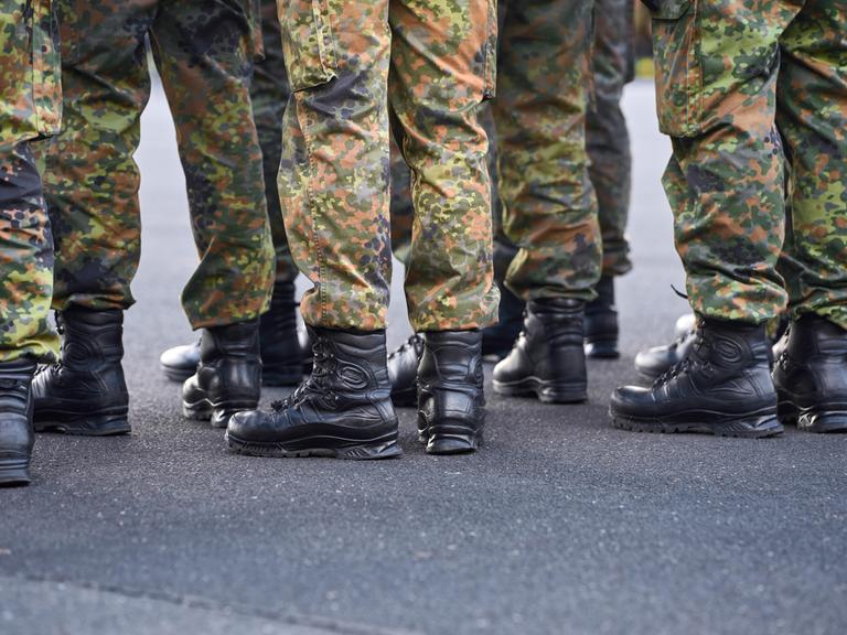 Schwarzen Einsatzstiefel und Tarnhosen von Soldaten der Bundeswehr, die in Formation stehen.