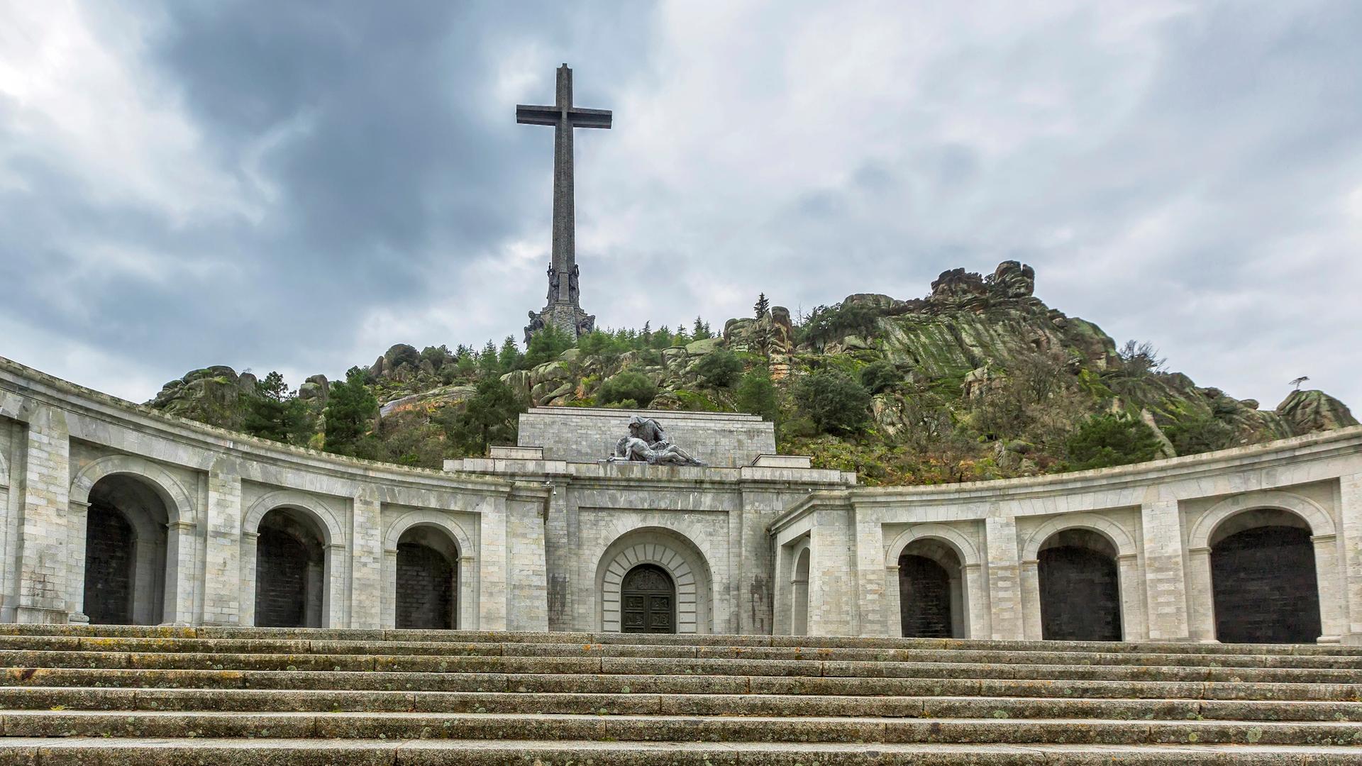 Valle de los Caídos mit einem hoch über felsige Hügel aufragendem Kreuz.