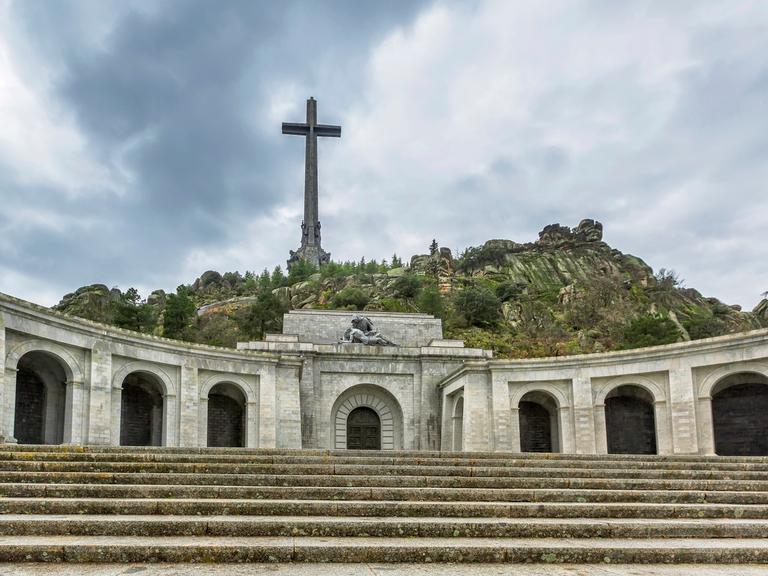 Valle de los Caídos mit einem hoch über felsige Hügel aufragendem Kreuz.