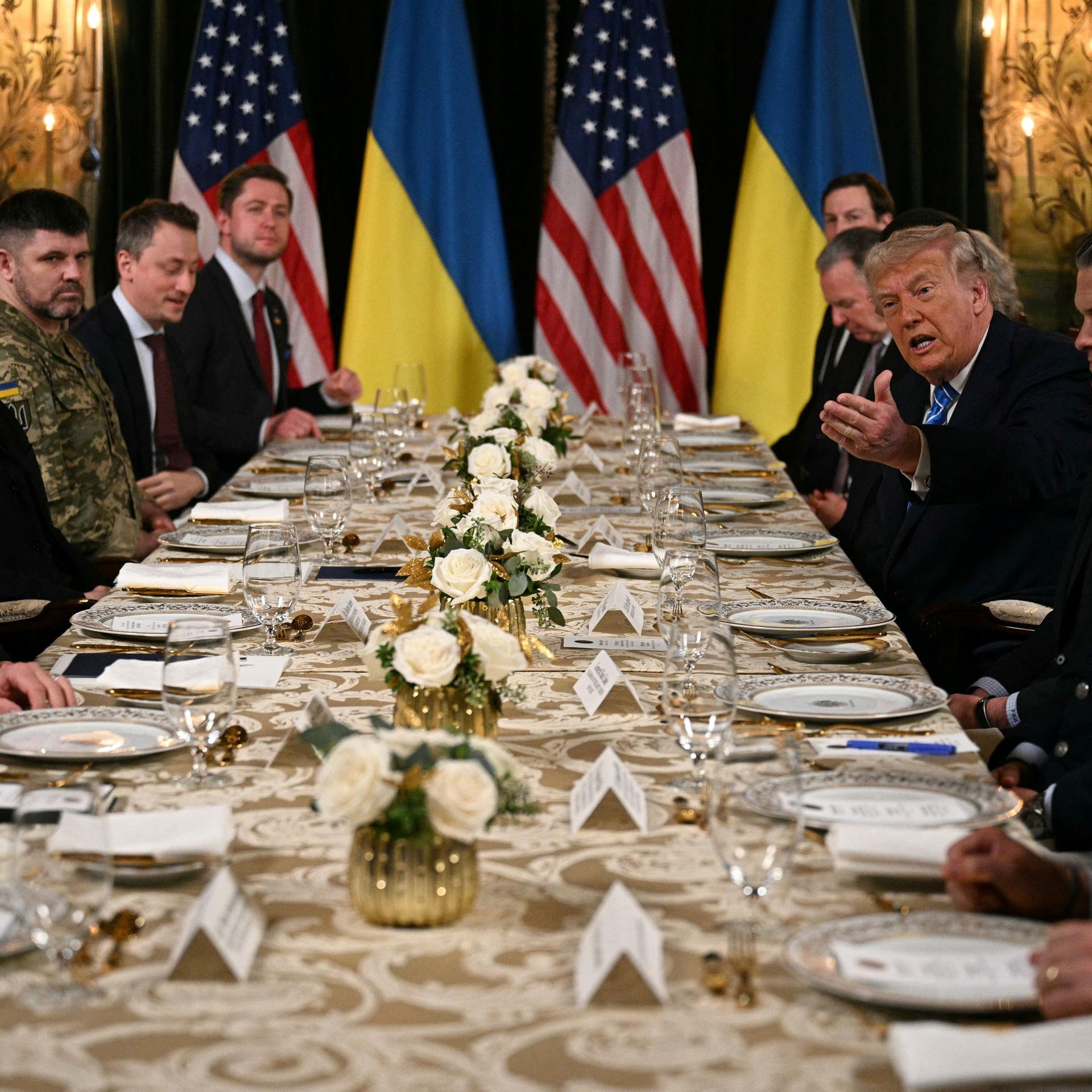 US-Präsident Trump empfängt den ukrainischen Präsidenten Selenskyj in Mar-a-Lago. Zusammen mit ihren Delegationen sitzen sie an einem langen Tisch.