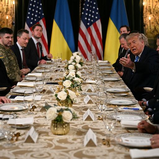US-Präsident Trump empfängt den ukrainischen Präsidenten Selenskyj in Mar-a-Lago. Zusammen mit ihren Delegationen sitzen sie an einem langen Tisch.