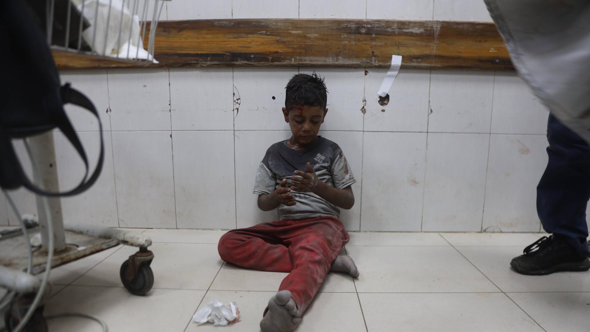 Ein verletzter Junge sitzt auf dem Boden von einem Kranken-Haus im Gaza-Streifen.