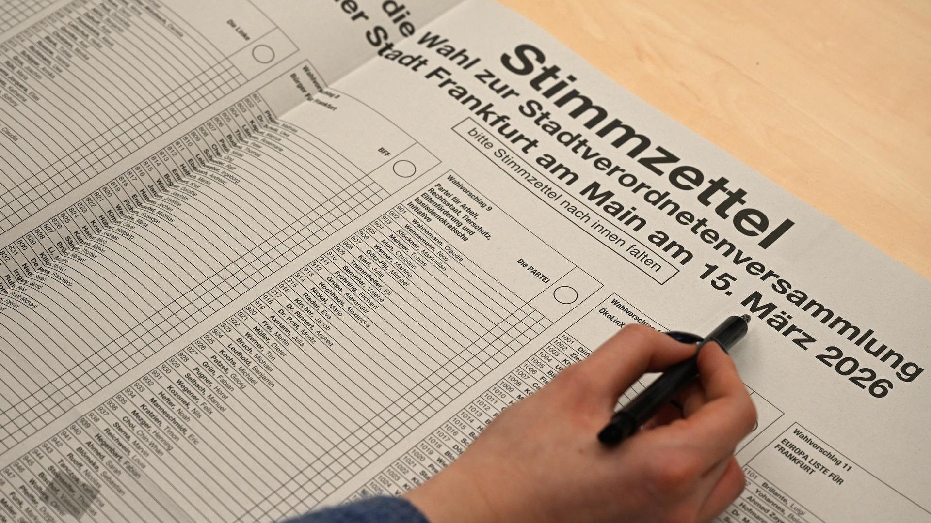 Eine Frau hält einen Stift an einen Stimmzettel zur Kommunalwahl in Frankfurt am Main. Eine Frau hält einen Stift an einen Stimmzettel zur Kommunalwahl in Frankfurt am Main.