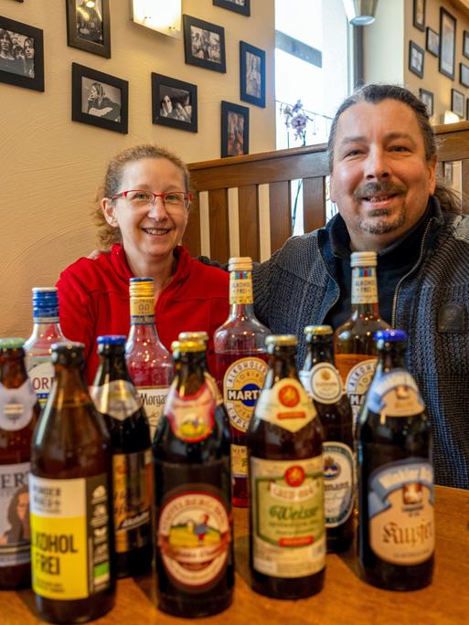 Kerstin Gößl und Vladimir Kloz sitzen hinter zahlreichen Flaschen alkoholfreier Biere und weiterer alkoholfreier Getränke
