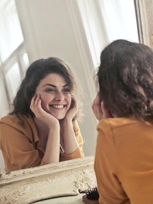 Eine junge Frau lächelt ihr Spiegelbild an
