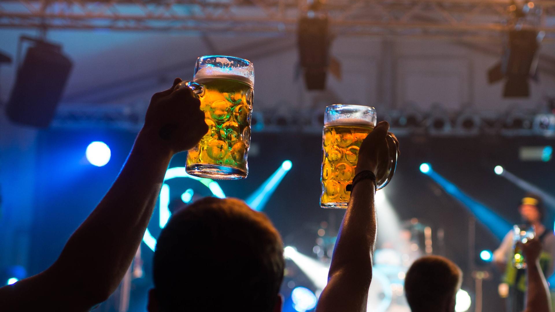 Kellerkomando Zuschauer heben ihre Bierkruege Mass waehrend einem Konzert der Band Kellerkommando