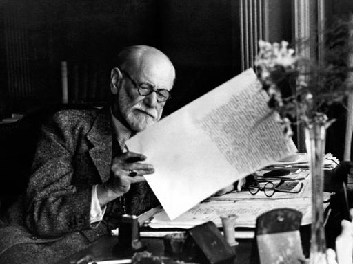 Ein historisches schwarz-weiß-Foto zeigt Sigmund Freud beim Verfassen eines Briefs. Aufnahmedatum unbekannt.