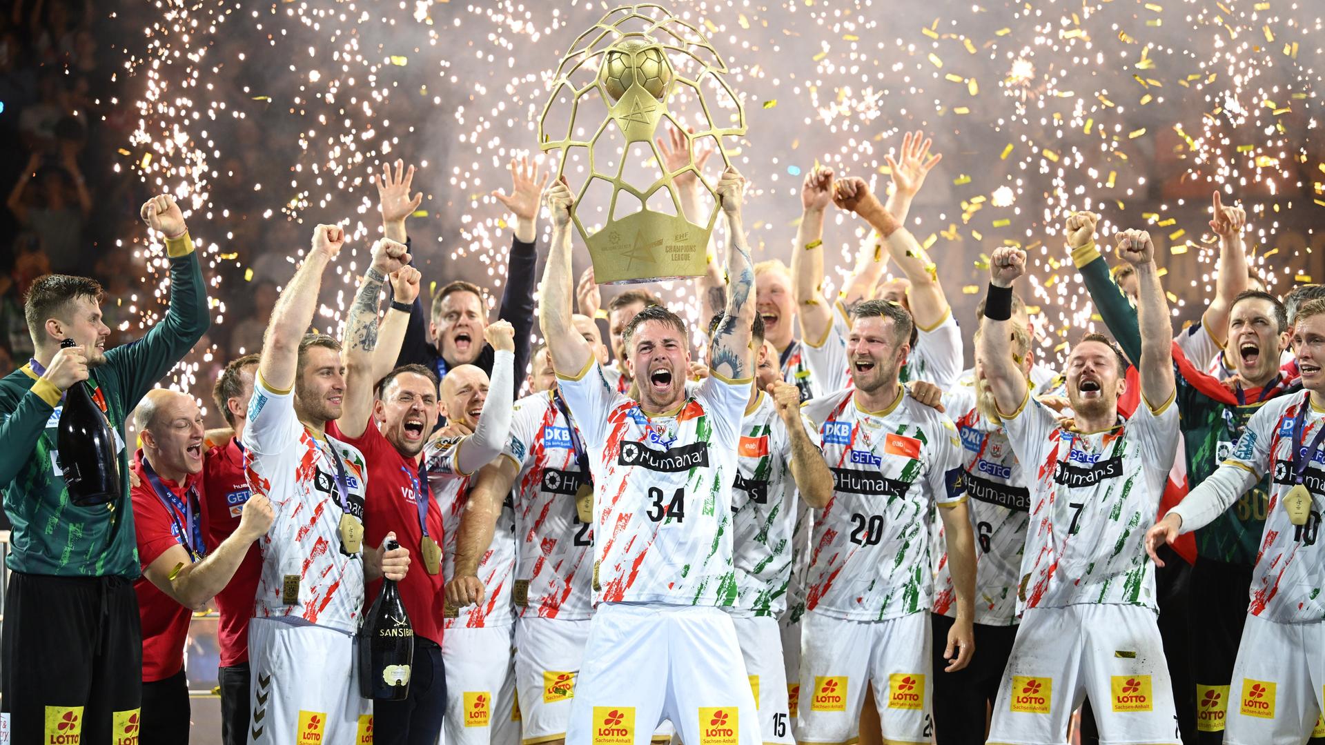 Die Spieler in den weißen Trikots reißen jubend die Arme hoch. Im Hintergrund sieht man weiße Funken emposchießen. Die Spieler in den weißen Trikots reißen jubend die Arme hoch. Im Hintergrund sieht man weiße Funken emposchießen.