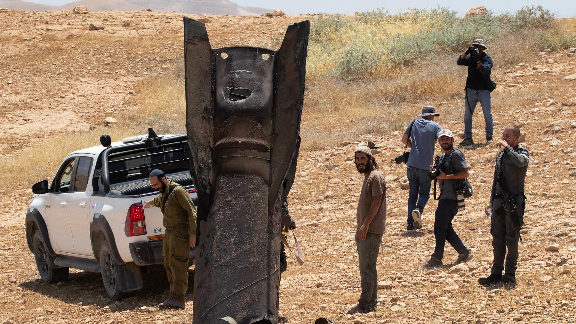 Eine iranische ballistische Rakete ragt aus der Wüstenlandschaft nahe Jericho im Westjordanland, nachdem sie von Israel abgefangen worden war. Männer stehen um die Rakete herum. Eine iranische ballistische Rakete ragt aus der Wüstenlandschaft nahe Jericho im Westjordanland, nachdem sie von Israel abgefangen worden war. Männer stehen um die Rakete herum.