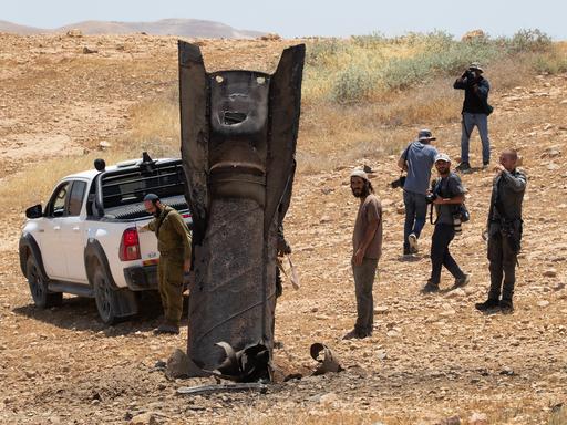 Eine iranische ballistische Rakete ragt aus der Wüstenlandschaft nahe Jericho im Westjordanland, nachdem sie von Israel abgefangen worden war. Männer stehen um die Rakete herum. Eine iranische ballistische Rakete ragt aus der Wüstenlandschaft nahe Jericho im Westjordanland, nachdem sie von Israel abgefangen worden war. Männer stehen um die Rakete herum.