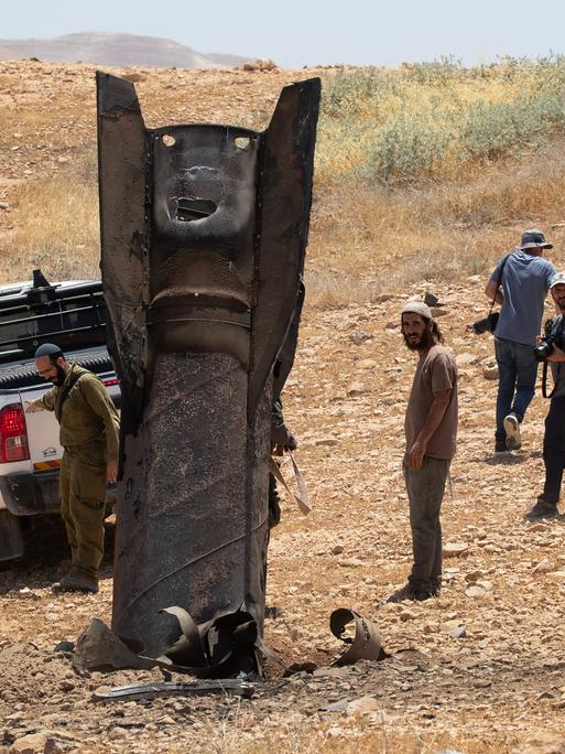 Eine iranische ballistische Rakete ragt aus der Wüstenlandschaft nahe Jericho im Westjordanland, nachdem sie von Israel abgefangen worden war. Männer stehen um die Rakete herum. Eine iranische ballistische Rakete ragt aus der Wüstenlandschaft nahe Jericho im Westjordanland, nachdem sie von Israel abgefangen worden war. Männer stehen um die Rakete herum.