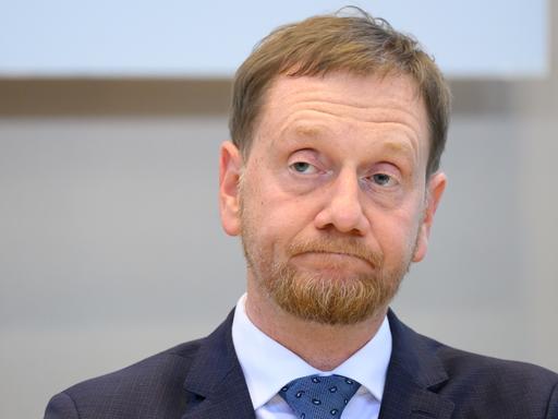 Michael Kretschmer von der CDU. Er ist der Minister-Präsident von Sachsen. Er verzieht das Gesicht. 