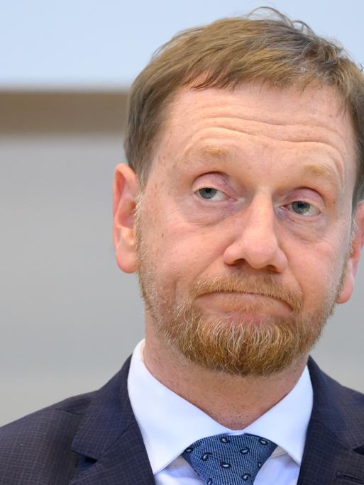 Michael Kretschmer von der CDU. Er ist der Minister-Präsident von Sachsen. Er verzieht das Gesicht. 