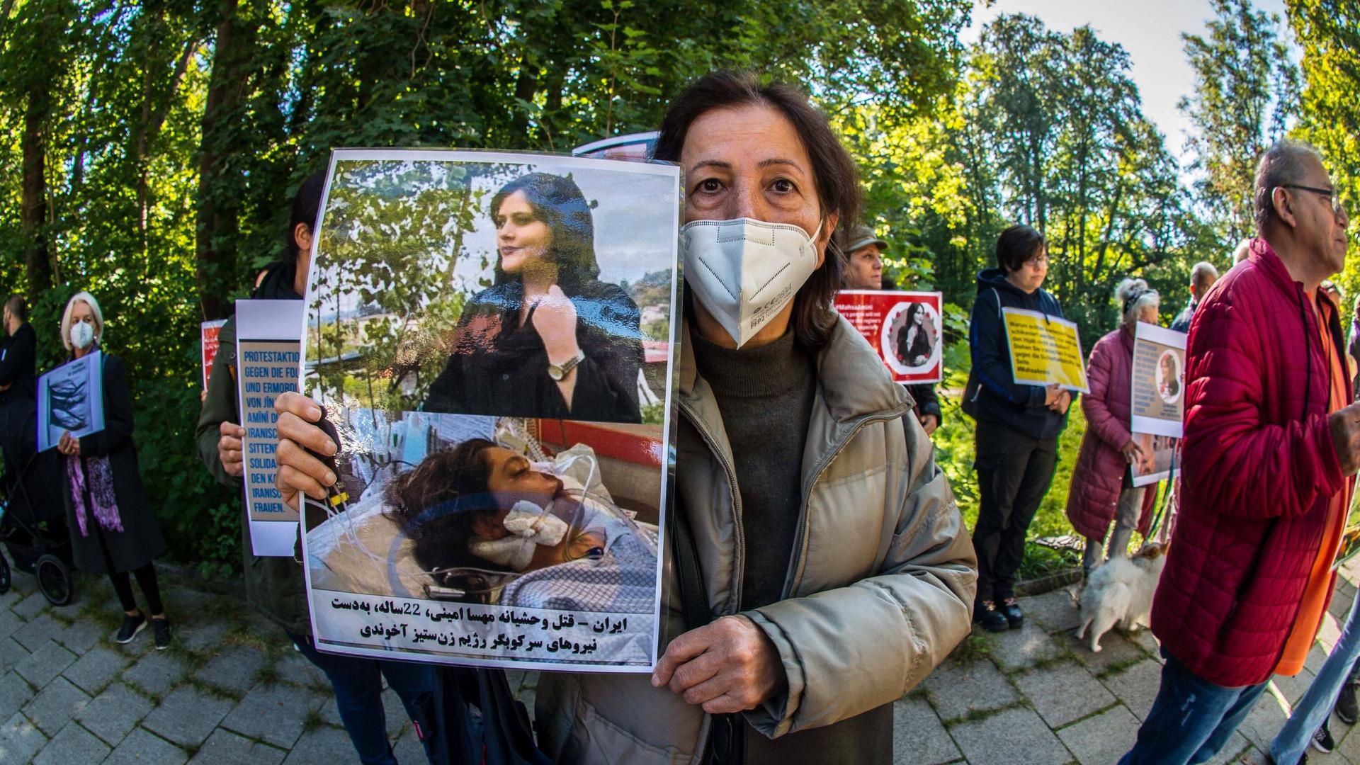 Eine Frau mit einem Plakat protestiert vor dem iranischen Konsulat in München gegen Unterdrückung von Frauen im Iran durch die Sittenpolizei.