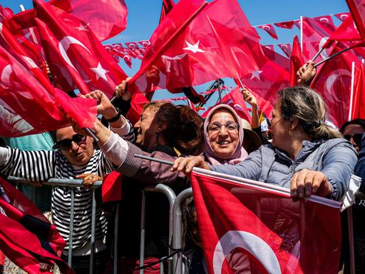 Ein Meer roter Fahnen mit zwei Frauen im Vordergrund bei einer Wahlveranstaltung n der Türkei 