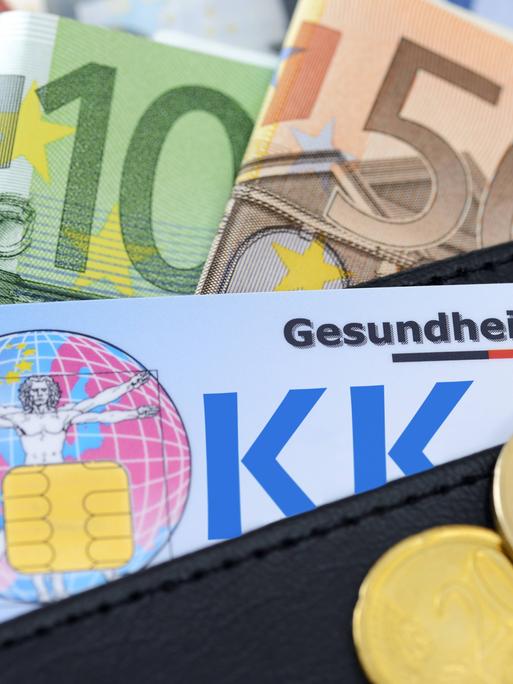 Eine Gesundheitskarte in einer Geldbörse. Drumherum liegen Euroscheine.