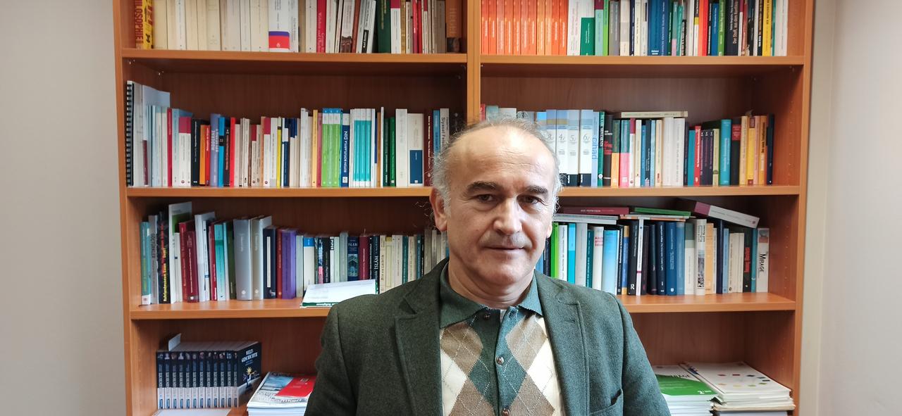 Der Religionswissenschaftler Ertuğrul Şahin im grauen Sakko vor einer Bücherwand.