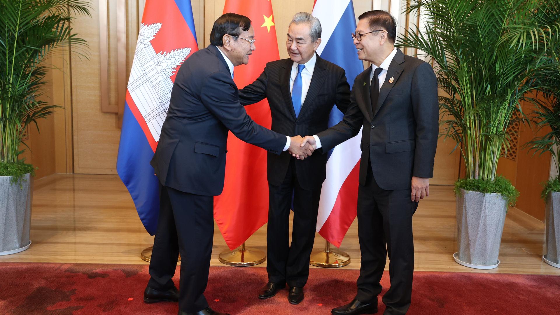 Der kambodschanische Außenminister Prak Sokhonn (l) schüttelt die Hand seines thailändischen Amtskollegen Sihasak Phuangketkeow (r) vor dem chinesischen Amtskollegen Wang Yi in der Provinz Yunnan, China. 