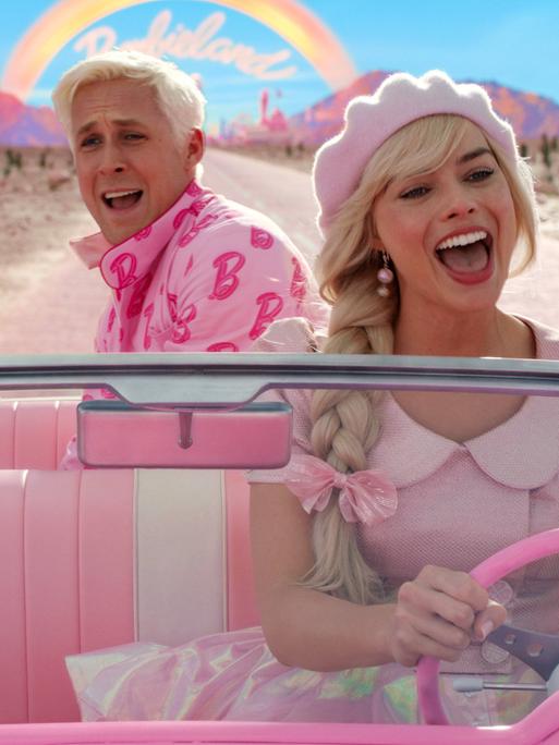 Ryan Gosling und Margot Robbie sitzen in einem Auto im Kinofilm "Barbie".