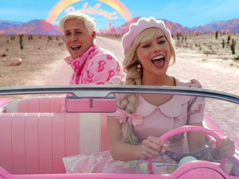 Ryan Gosling und Margot Robbie sitzen in einem Auto im Kinofilm "Barbie".